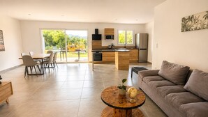 A modern living room with a sofa, a round coffee table, and a dining area with chairs. - Villa 'Des Rives Et Chevaux 07' with Private Pool, Wi-Fi and Air Conditioning (Montréal)