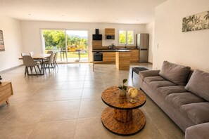 Ein modernes Wohnzimmer mit einer Couch, einem runden Couchtisch und einem Essbereich mit Stühlen.