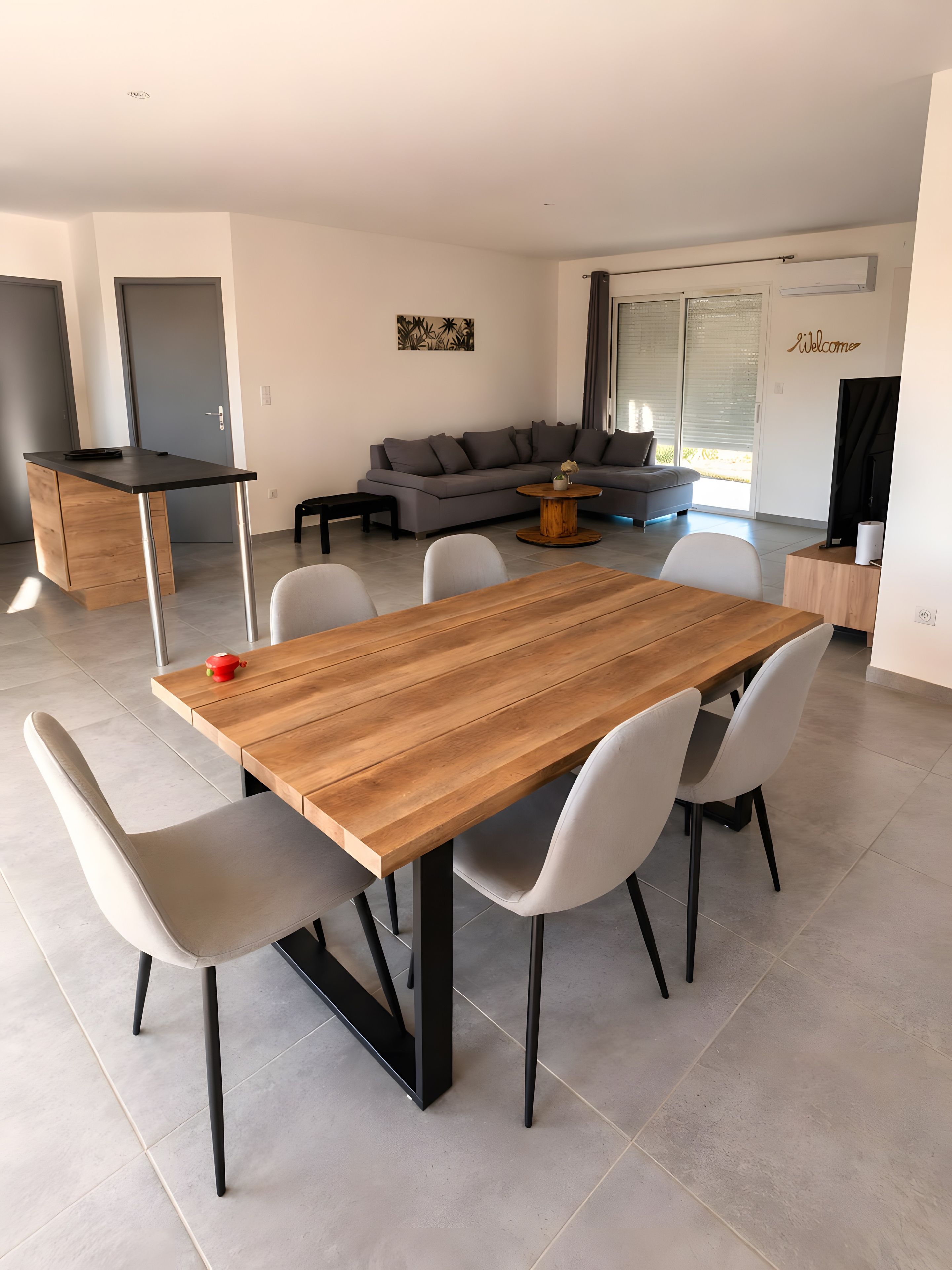 A modern living space with a dining area featuring a wooden table and chairs, a grey sofa, and a small coffee table.