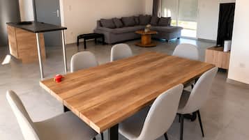 A modern living space with a dining area featuring a wooden table and chairs, a grey sofa, and a small coffee table.