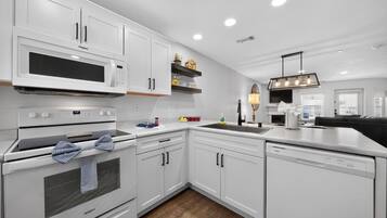 A modern kitchen with white cabinetry, a built-in microwave, and a dishwasher.