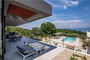 A modern outdoor patio with a dining area, lounge seating, and a swimming pool. - Villa Moana (Vrbnik)
