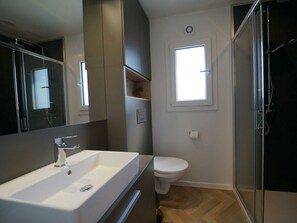 Een badkamer met een wit wastafel, toilet en douche.