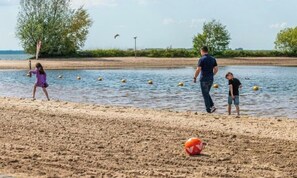 Een strand met een volleybalnet, een volleybal en mensen die spelen.