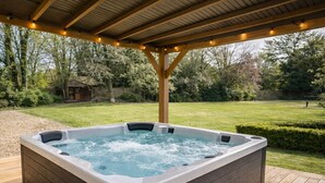 A hot tub on a wooden deck with a pergola overhead. - Elegy House (Slough)