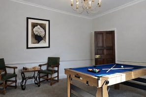 A room with a pool table, two chairs, a framed picture, and a door. - Elegy House (Slough)