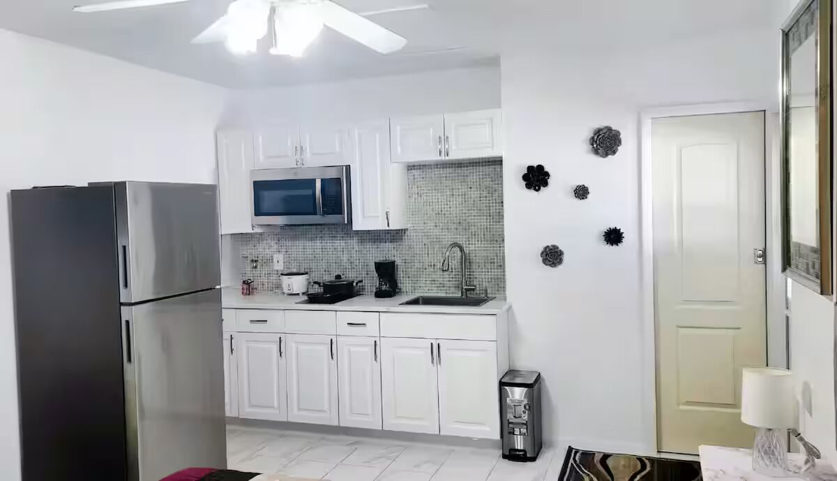A kitchen with white cabinets, a stainless steel refrigerator, a microwave, and a coffee maker.