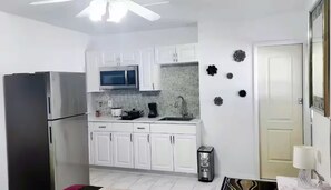 A kitchen with white cabinets, a stainless steel refrigerator, a microwave, and a coffee maker. - Charming bedroom with kitchen (Spring Hill)