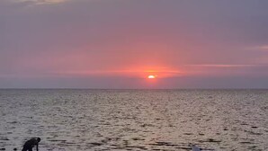 Auringonlasku tyynen meren yllä, ja etualalla näkyy ihmisen hahmo siluettina.
