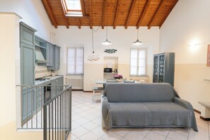 A spacious kitchen with a dining area, a sofa, and a staircase. - Varenna Boulevard: Spacious Apartment in the City Center (Varenna)