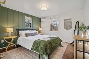 Een slaapkamer met een bed, nachtkastjes, een raam en een spiegel.