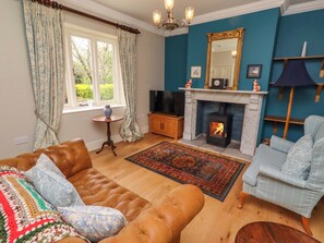Una sala de estar con sofá, sillón, chimenea, televisor y vista al exterior.