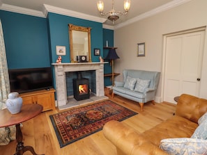 A living room with a fireplace, sofa, television, and decorative items. - 9 Longhirst Village (Morpeth)