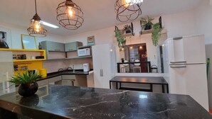 A modern kitchen with a marble countertop, pendant lighting, and a view into the dining area.