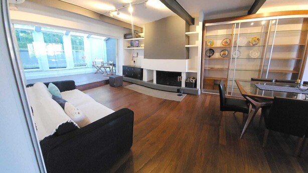 A modern living room with a fireplace, a dining area, and a view of the outdoors.