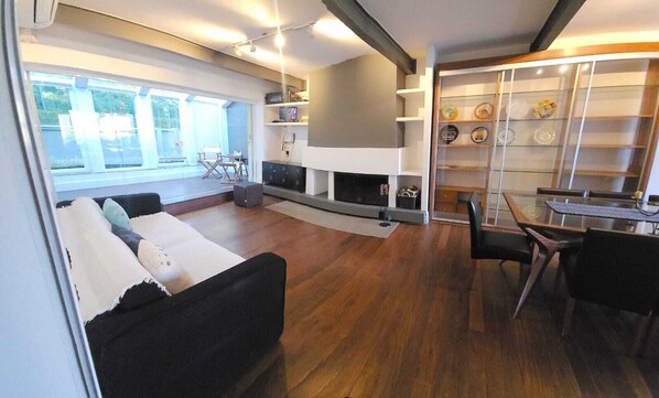 A modern living room with a fireplace, a dining area, and a view of the outdoors.