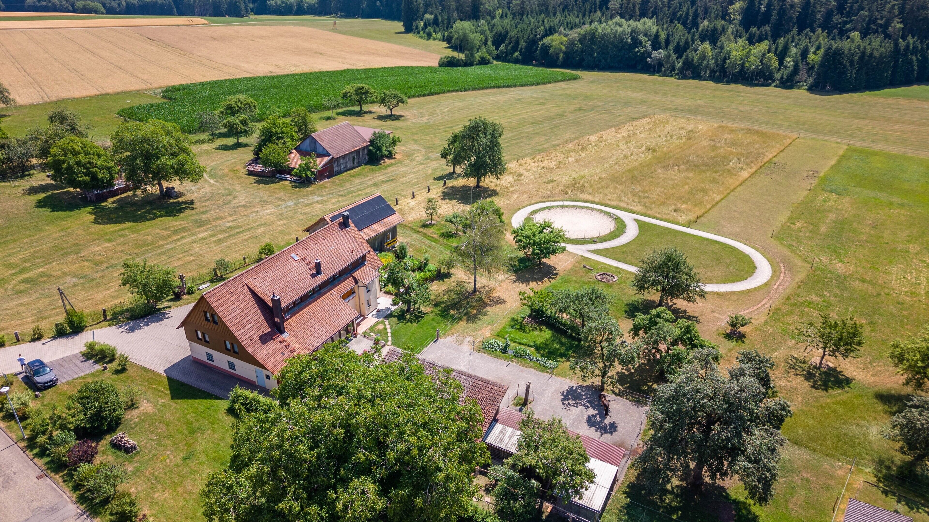 Une propriété rurale dotée d’une grande grange, d’une allée et d’un champ circulaire.