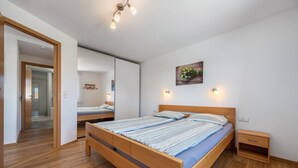Een slaapkamer met een houten bed, nachtkastjes, een spiegel en een wandlamp.