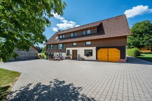 Ein zweigeschossiges Gebäude mit einem Ziegeldach, einer gepflasterten Auffahrt und einem Vorgarten.