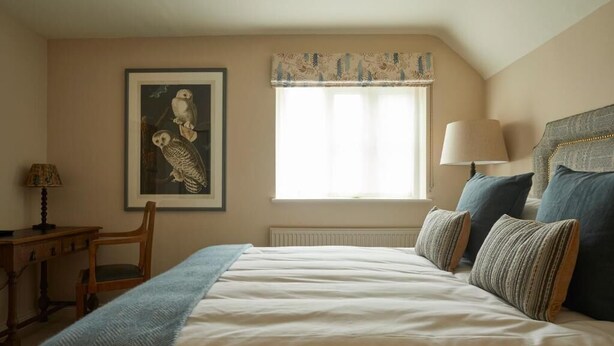 A bedroom with a bed, a window with curtains, a lamp, a chair, and a framed picture on the wall. - Crown and Anchor Ham (Marlborough)