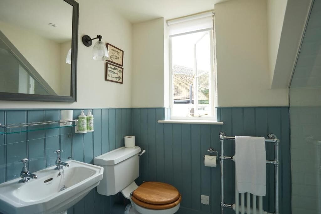 A bathroom with a sink, toilet, and window.