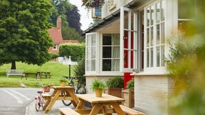 A pub with outdoor seating, a bicycle, and a sign in the background. - Crown and Anchor Ham (Marlborough)
