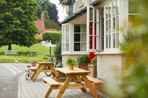 A pub with outdoor seating, a bicycle, and a sign in the background. - Crown and Anchor Ham (Marlborough)