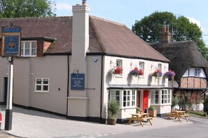A traditional building with a red door, outdoor seating, and flower baskets.