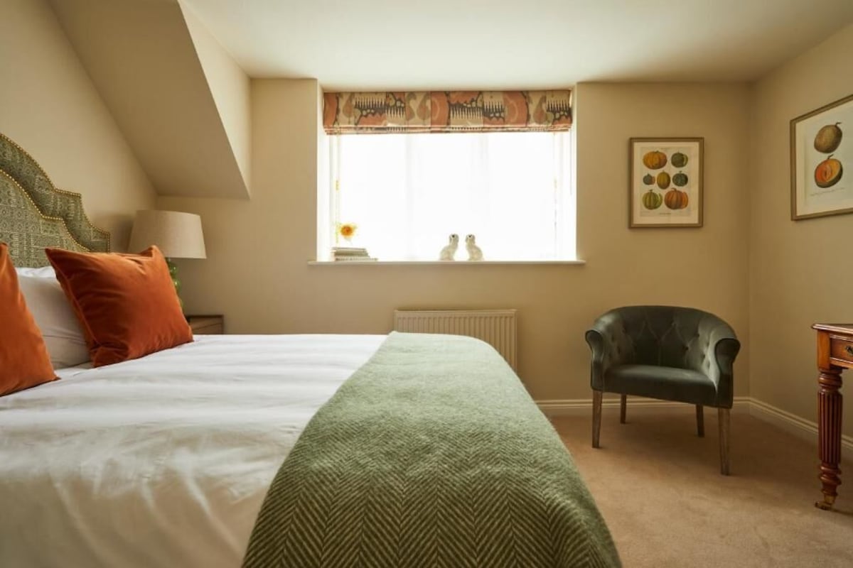 A bedroom with a bed, a chair, a window with a view, and a radiator.