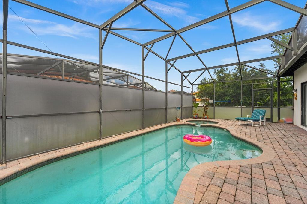A swimming pool with a glass enclosure, a lounge chair, and a small inflatable ring.