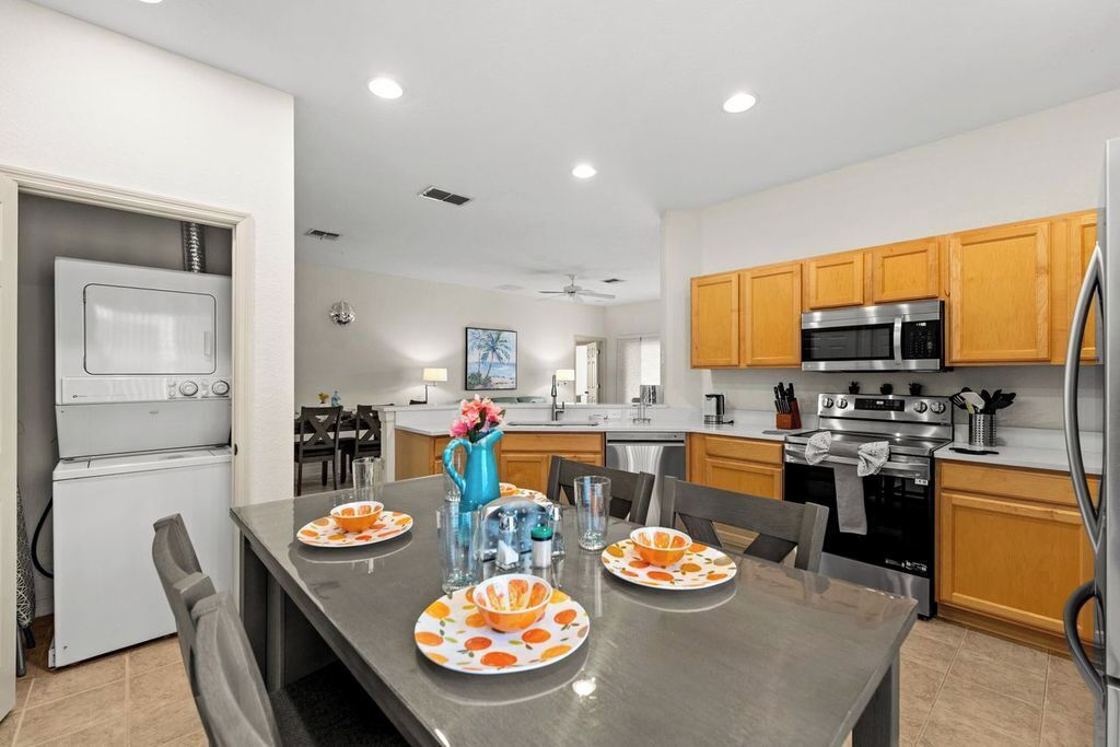A modern kitchen with stainless steel appliances, wooden cabinets, and a dining area with orange plates.