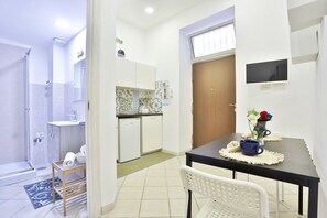 A modern bathroom with a shower, toilet, and sink. There is a small dining area with a table and chairs. - A cozy apartment perfect for two people, located on the ground floor of a building near the Spanish Quarter, on the highest part of the hill and close to the Corso Vittorio Emanuele funicular. Comfortable and simple, with a direct entrance to the kitchen (Naples)