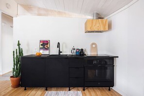 Eine moderne Küche mit schwarzen Schränken, einem eingebauten Ofen und einem Holzbodenabzug.