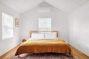 A bedroom with a bed, two windows, a ceiling fan, and a wooden floor. - Close to Downtown — The Cozy Bungalow (Austin)
