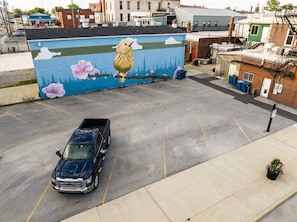 Ein Parkplatz mit Wandgemälde von einem Vogel und Blumen an einem Gebäude.