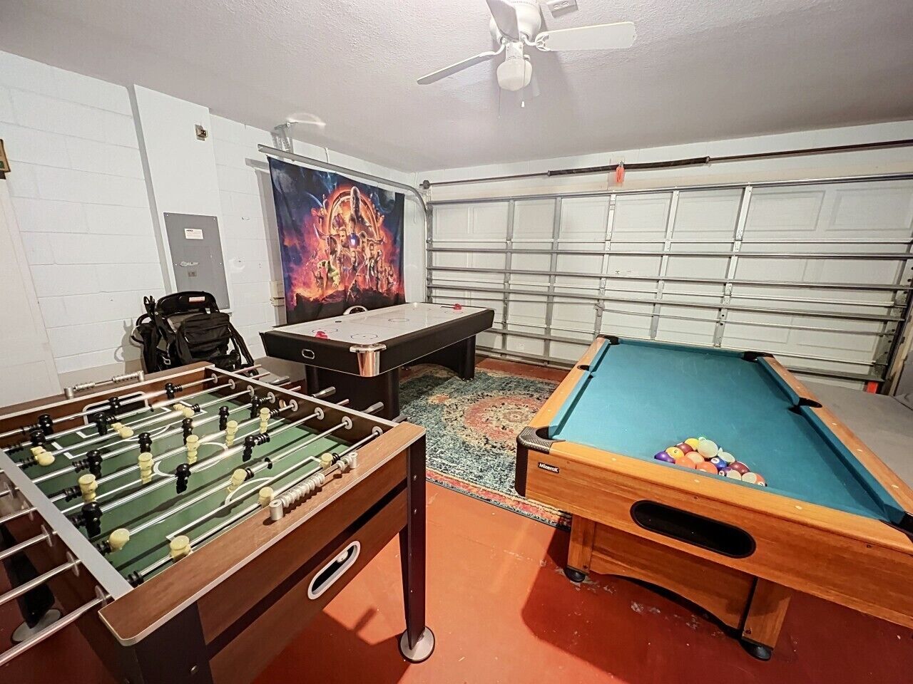 Een kamer met een tafelvoetbaltafel, een pooltafel en een groot poster aan de muur.
