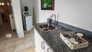 Una cocina con encimeras de granito, un lavamanos de acero inoxidable y un microondas.