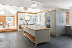 A modern kitchen with a central island, grey cabinetry, and a view to the outside.