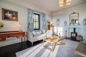A well-lit living room with a sofa, coffee table, fireplace, and decorative items.