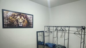 A bedroom with a bunk bed, a metal wardrobe with hanging space, a mirror, and a framed artwork of a lion. - Cozy and well-located apartment (Uberlândia)