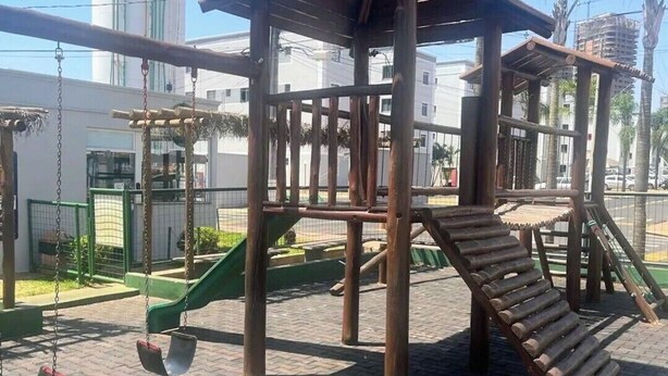 A playground with a wooden structure, swings, and a slide. - Cozy and well-located apartment (Uberlândia)