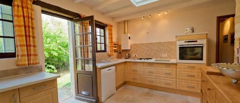 Una cocina con tragaluces, lavavajillas, estufa y armarios de madera.