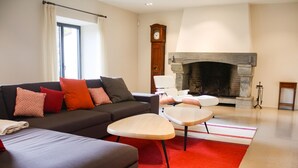 Ein Wohnzimmer mit einer Couch, Sesseln, einem Kamin und einer Uhr.