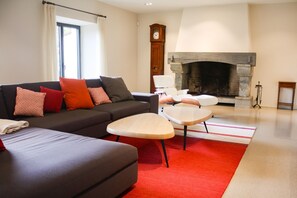 Ein Wohnzimmer mit einer Couch, Sesseln, einem Kamin und einer Uhr.