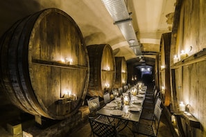 A long table set for dining in a room with wooden barrel walls, lit by candles.