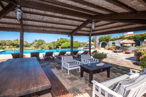 Eine Außenpatio mit Pool, Liegestühlen und einem Holztisch.