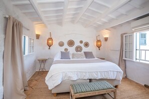 Ein Schlafzimmer mit einem Bett, Nachttischen, einer Bank und Wanddekoration.