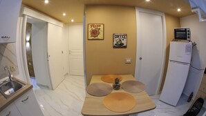 A compact kitchen with a microwave, refrigerator, and a small dining table with placemats. - Frontemare - Camera Positano (Naples)