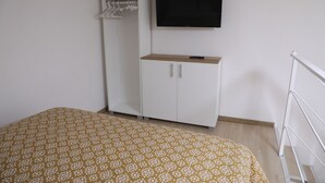 A bedroom with a bed, a wardrobe, a television, and a white metal ladder. - Frontemare - Camera Positano (Naples)