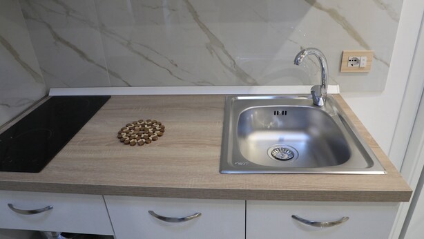 A kitchen with a stainless steel sink, a wooden countertop, and a marble backsplash. - Frontemare - Camera Positano (Naples)